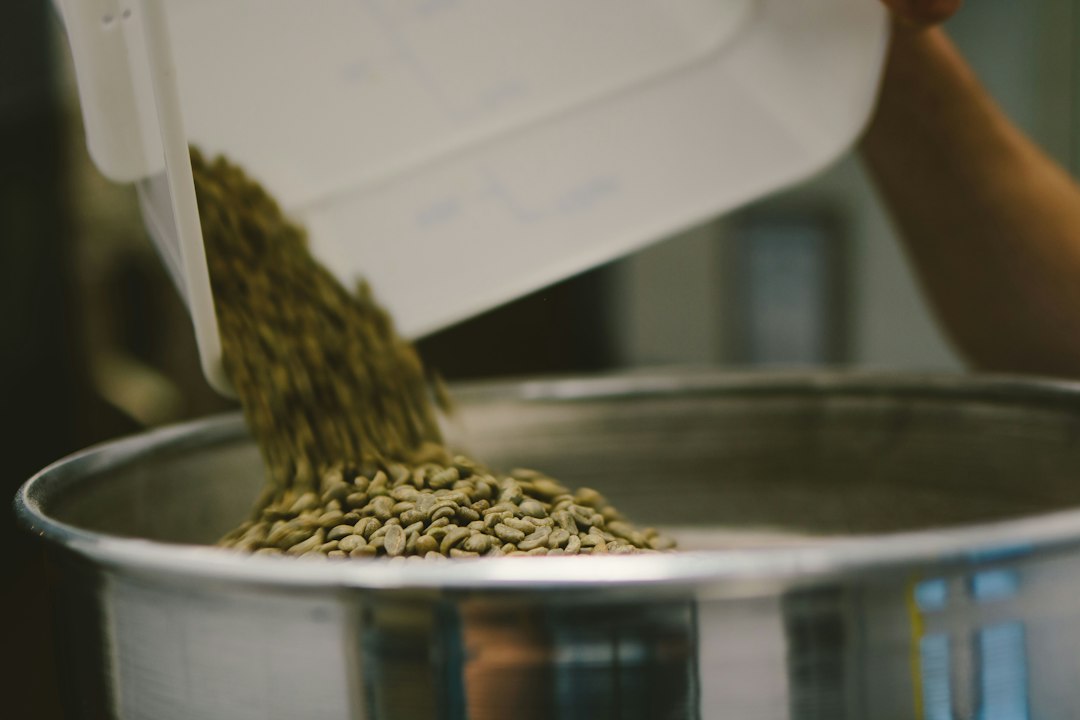 Green coffee beans being poured for roasting
